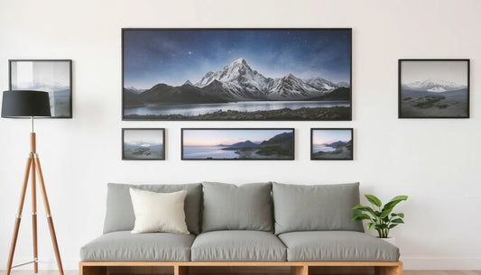 Stylish living room featuring a gray sofa, framed mountain landscape artwork, and a tall lamp, enhancing a cozy atmosphere.