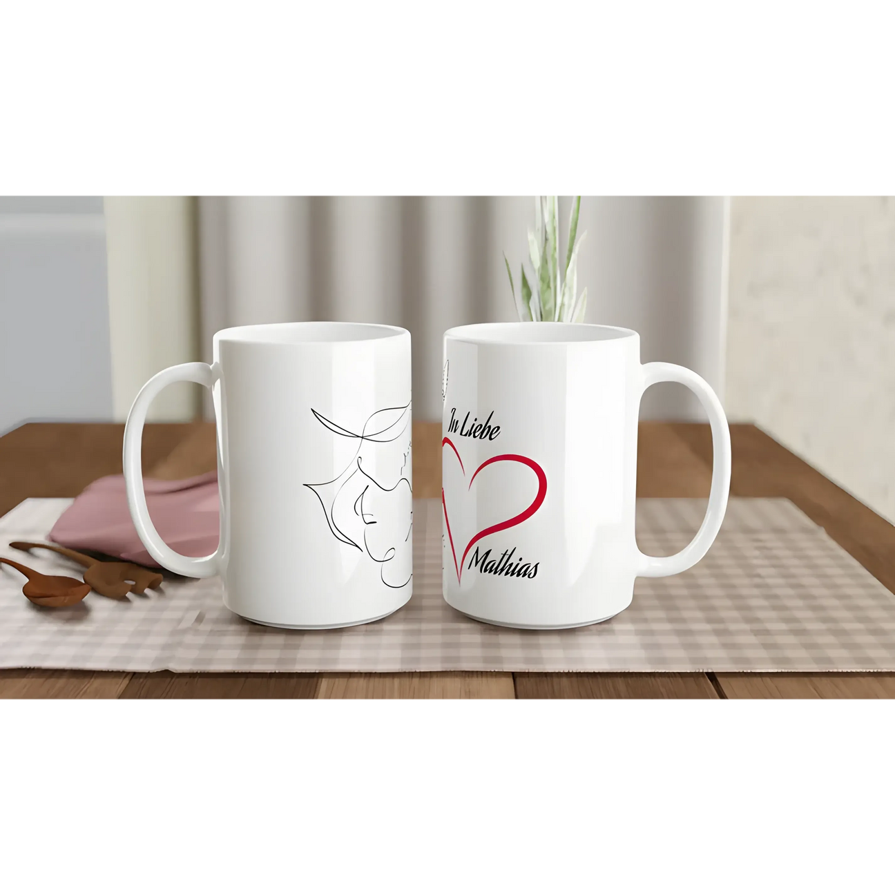 Two white ceramic mugs sit on a plaid tablecloth. One features a minimalist line drawing of a bull, while the other displays a red heart and the text "In Liebe Matthias."